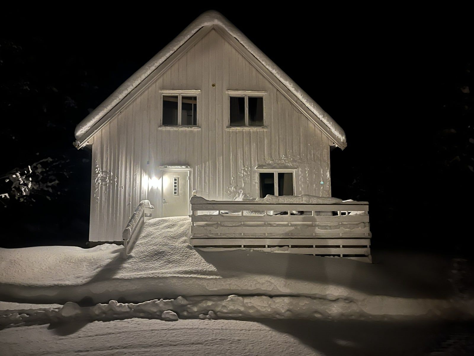 Gamle Ness en vinterkveld, med snø på taket og lys ved inngangen