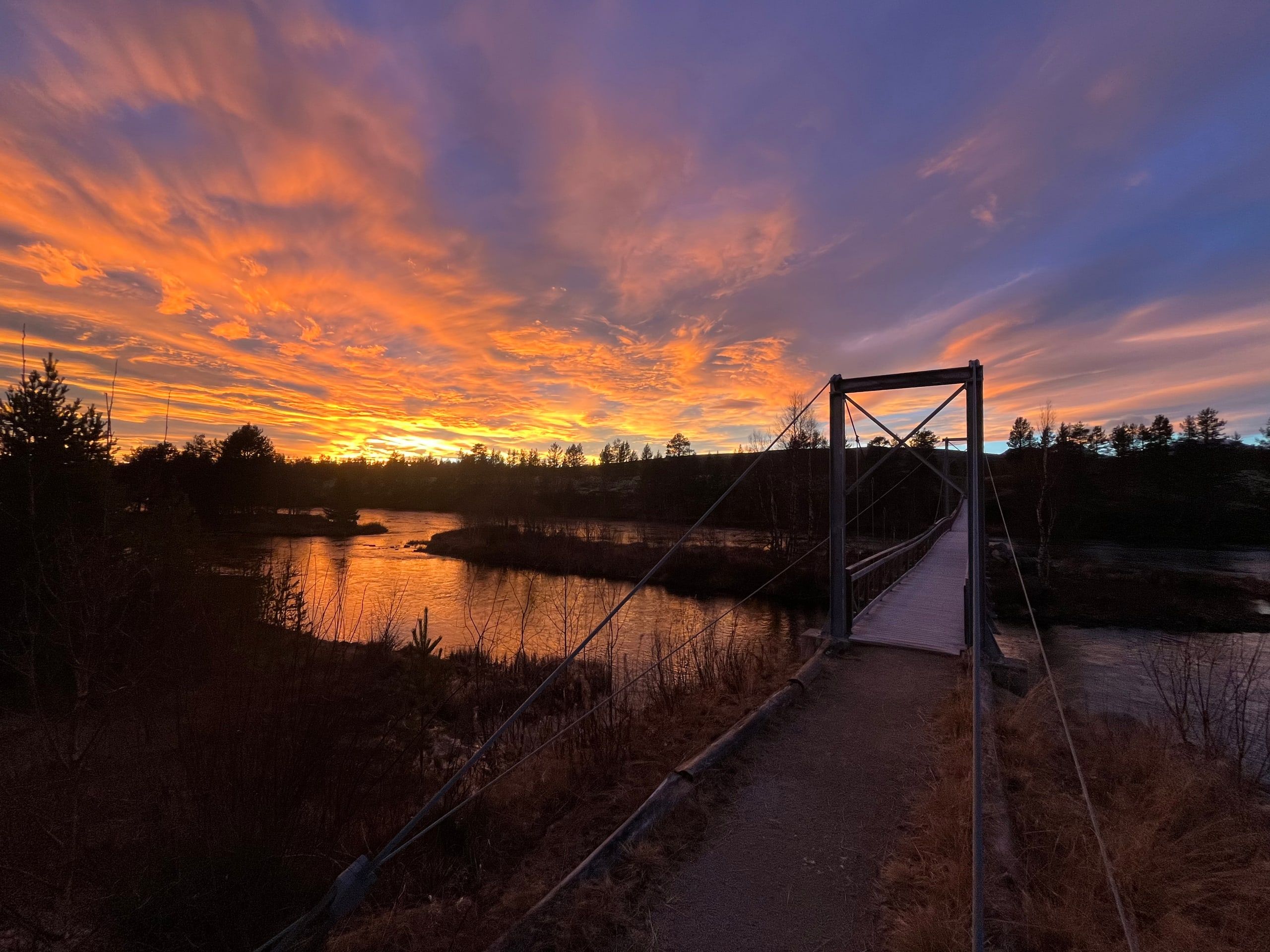 Gangbroa over Femundselva i solnedgang