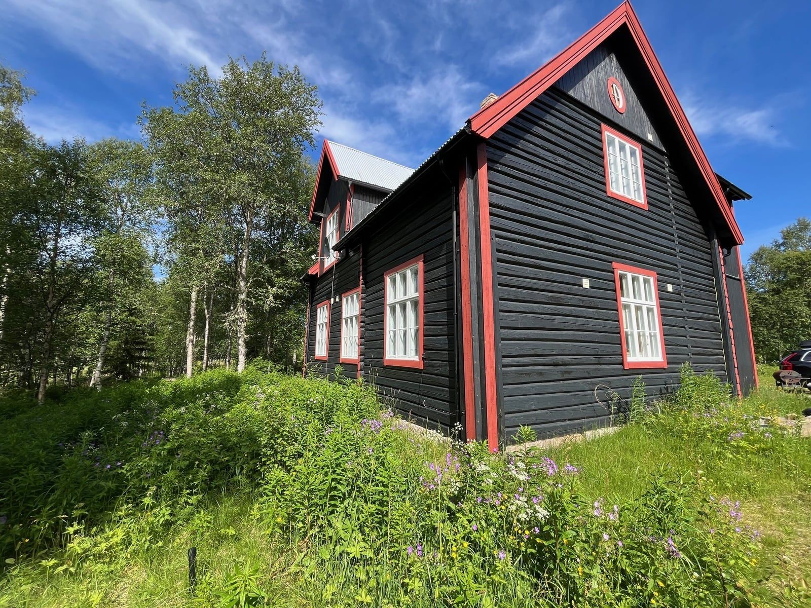 Tømmerhytta Skula fra siden en sommerdag, med bjørkeskog rundt