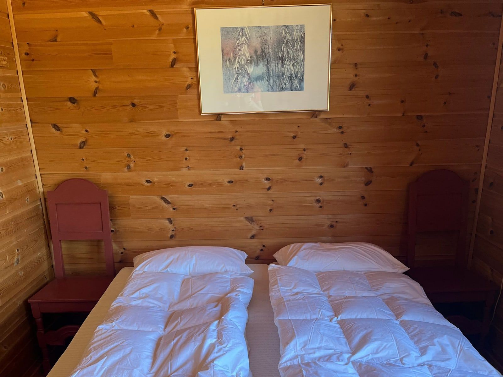Soverom med to senger, furupanel og rødmalte stoler